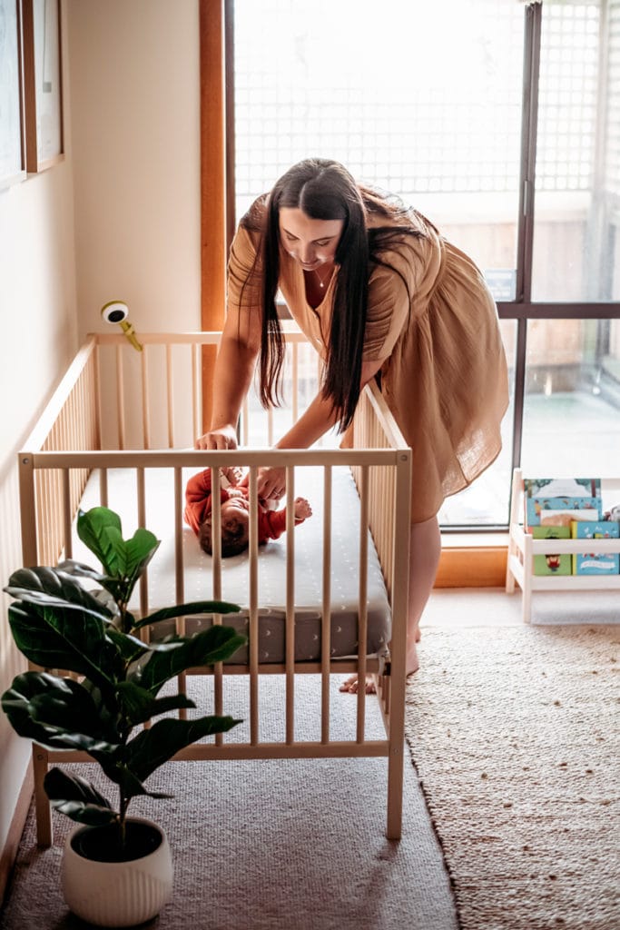 Newborn Photography, a mother lays her new baby to rest gently in the crib